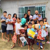 Crianças e voluntários reunidos com doações
